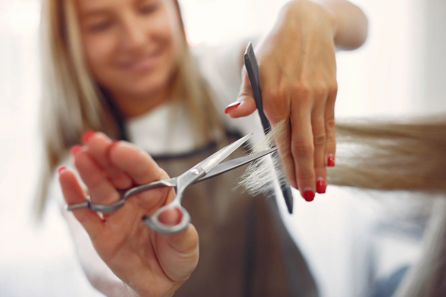 Die Spitzen einer Haarsträhne werden mit der Friseurschere geschnitten